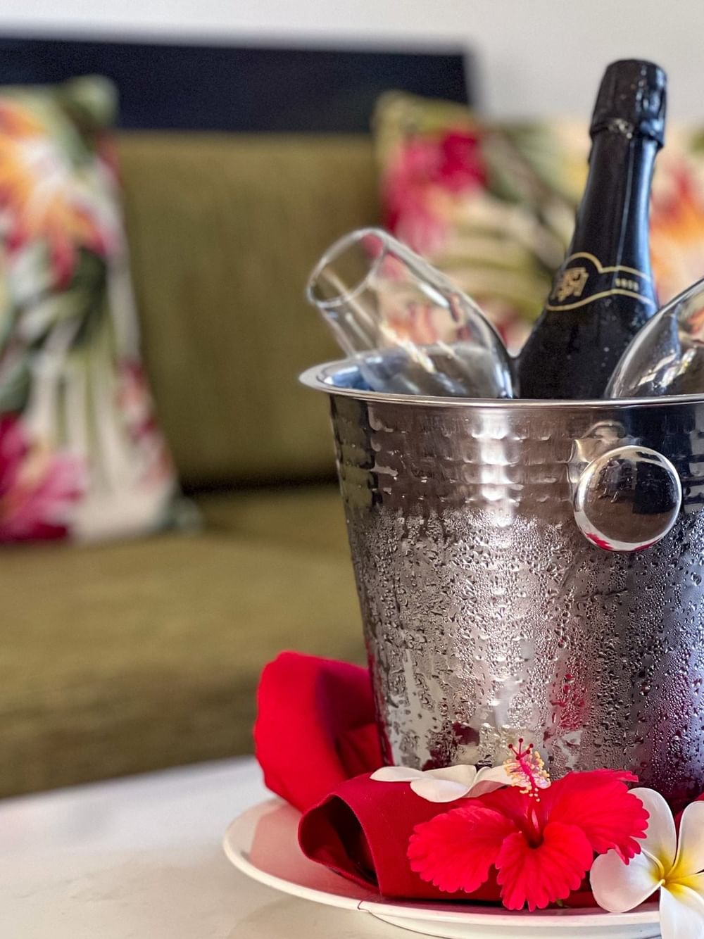 Bottle of wine in bucket with red napkins and tropical flowers on table at Tokatoka Resort - Fiji International Airport, Nadi.
