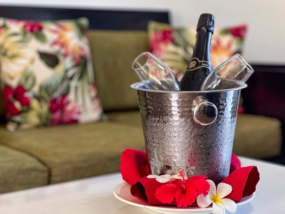 Bottle of wine in bucket with red napkins and tropical flowers on table at Tokatoka Resort - Fiji International Airport, Nadi.