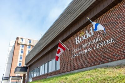 Brick exterior of the Convention Centre at Rodd Grand Yarmouth, flying the Canadian flag under a bright blue sky