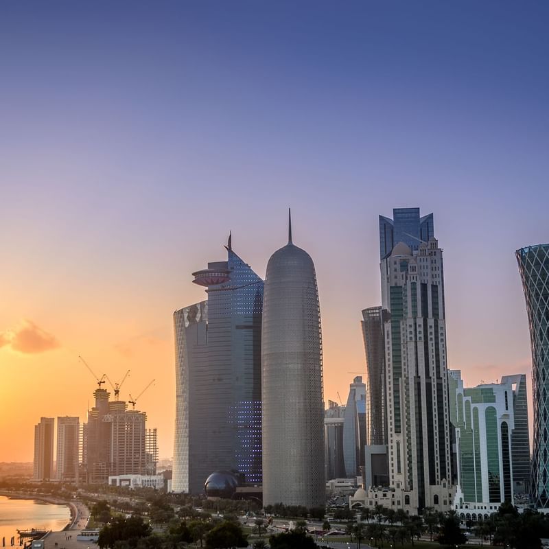 Doha skyline showcases distinctive skyscrapers, with cranes indicating ongoing construction near Warwick Hotels and Resorts