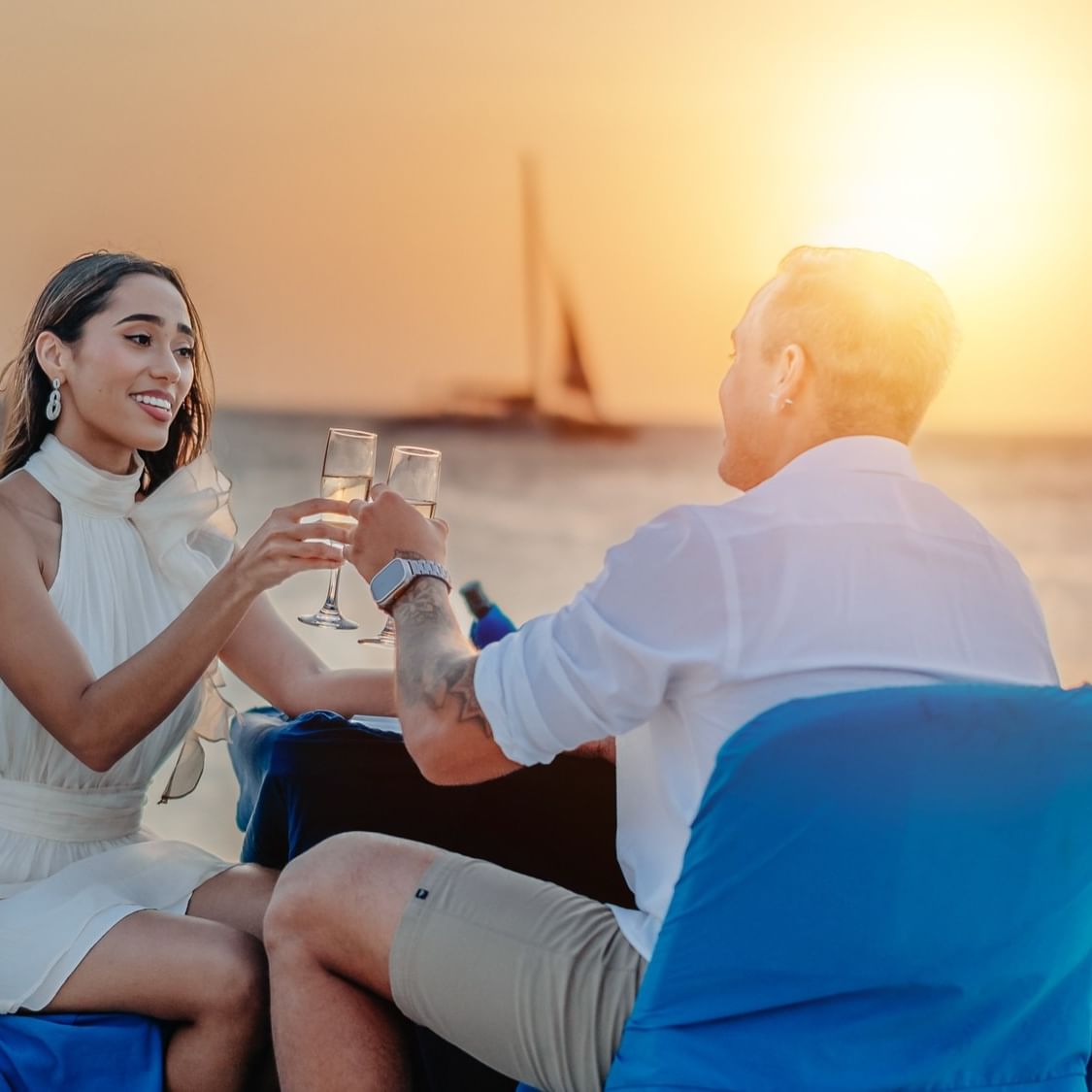 Couple toasting with champagne glasses at sunset on the beach for Valentine's Day.