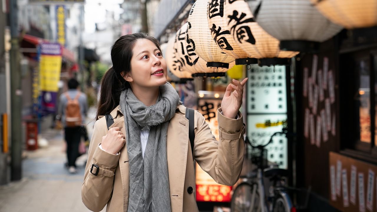 girl looking at paper lanterns hanging in Osaka