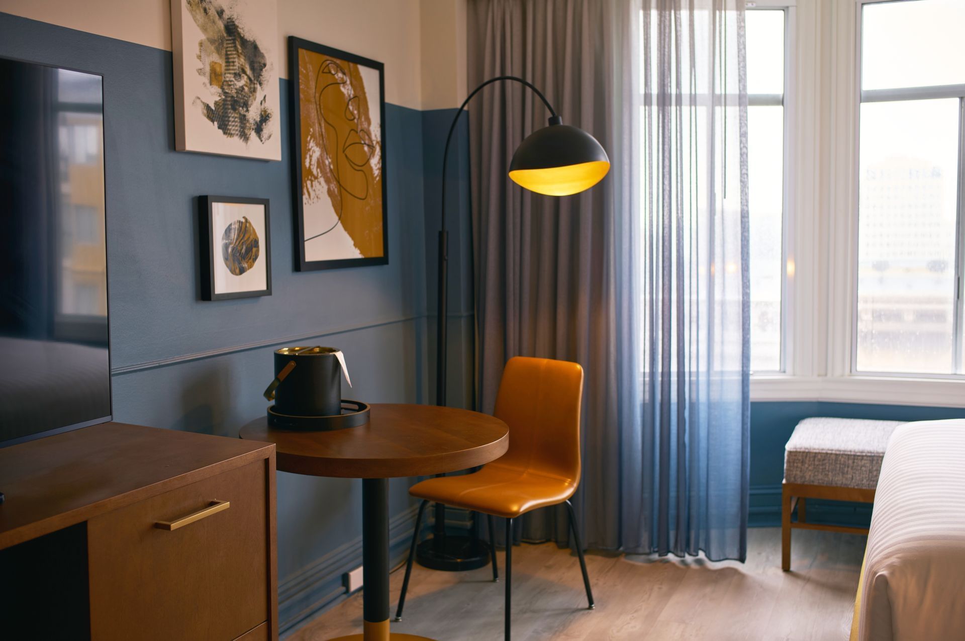 A hotel room with a desk, chair, lamp, and bed