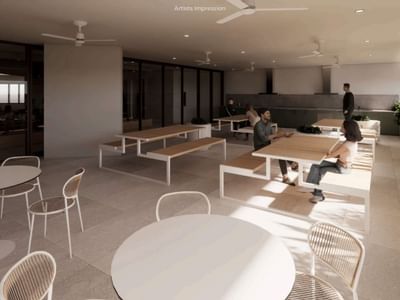People sitting and standing in a communal space with tables and chairs at UniLodge Brisbane City.