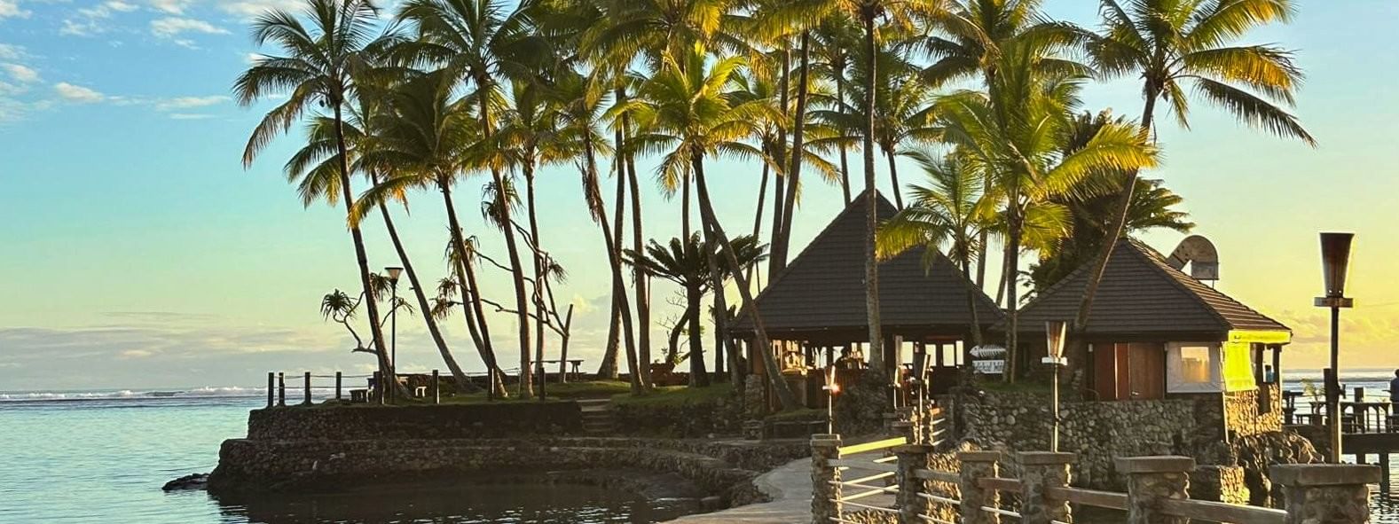 Exterior view of Wicked Walu with stone walkway by the ocean leading to huts under palm trees at Warwick Fiji Resort and Spa