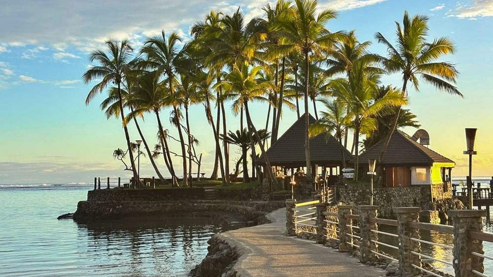 Exterior view of Wicked Walu with stone walkway by the ocean leading to huts under palm trees at Warwick Fiji Resort and Spa