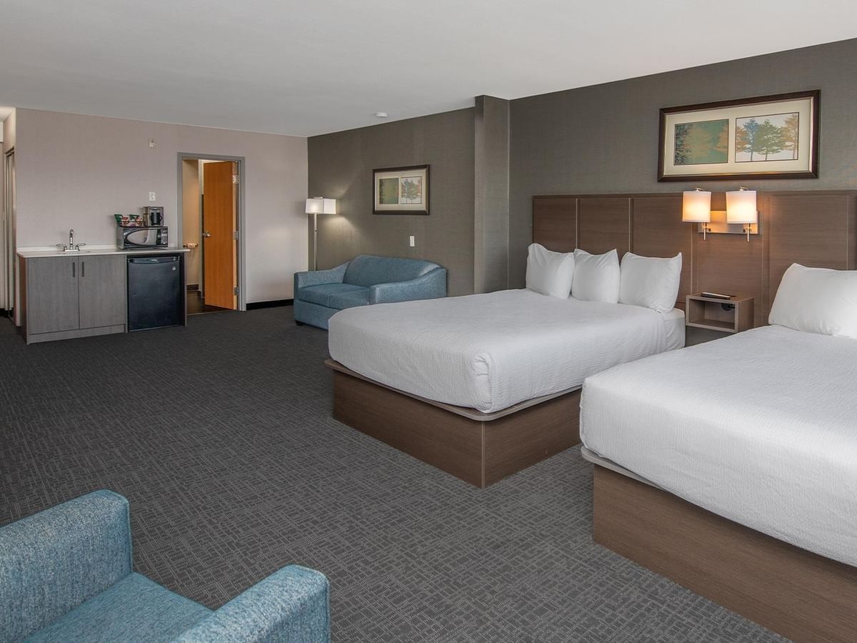 Two queen beds, sofa bed, and desk in a hotel room.