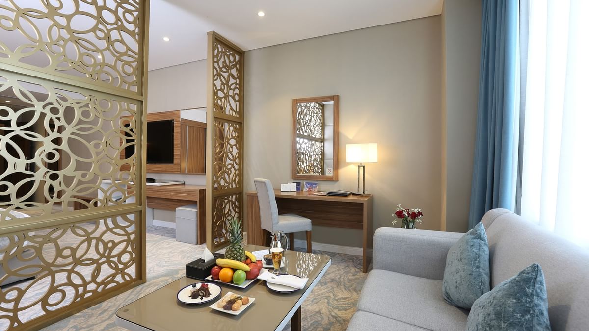 Junior Suite with a couch, coffee table, and desk at Cantonal Hotel by Warwick Riyadh.