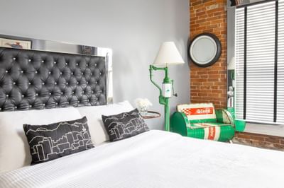 Queen bed with comfy pillows, standing lamp & oil drum seat in Queen Premiere Easy Rider at Retro Suites Hotel