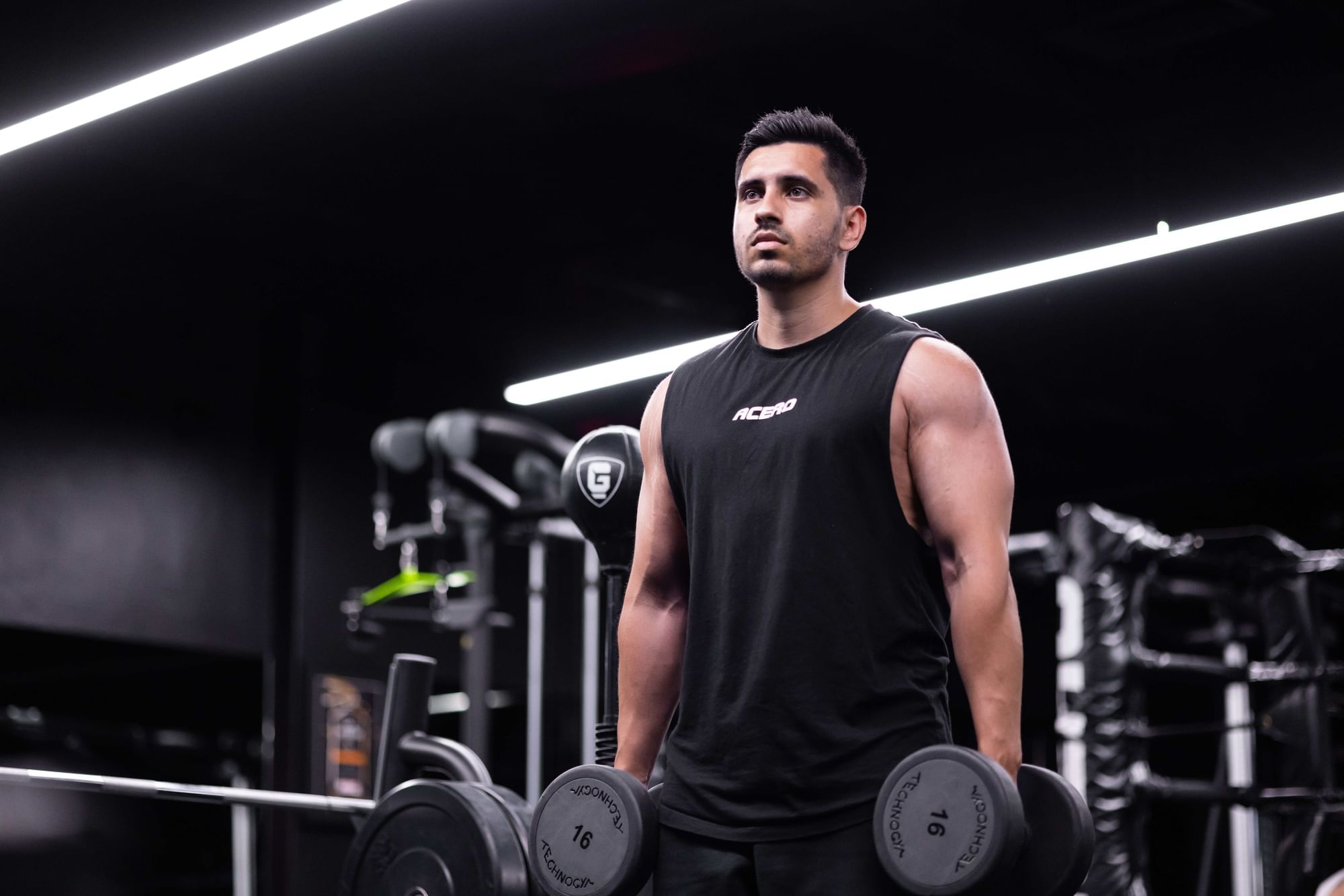 Man in a black tank top lifting weights at the gym at Fullerton Group