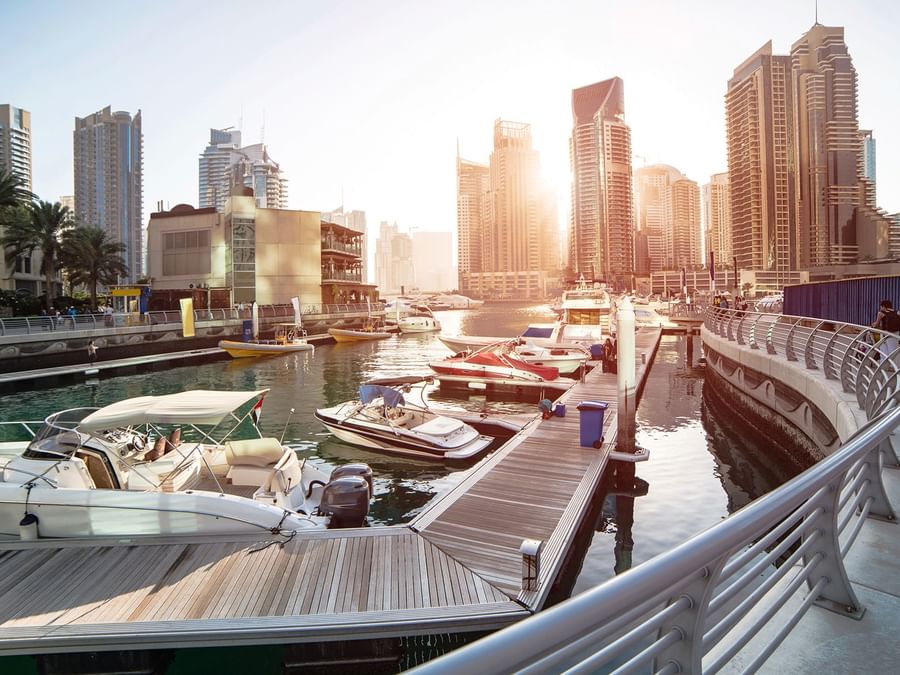 Sunset at a modern marina with boats, surrounded by high-rise buildings near DAMAC Hotels & Resorts