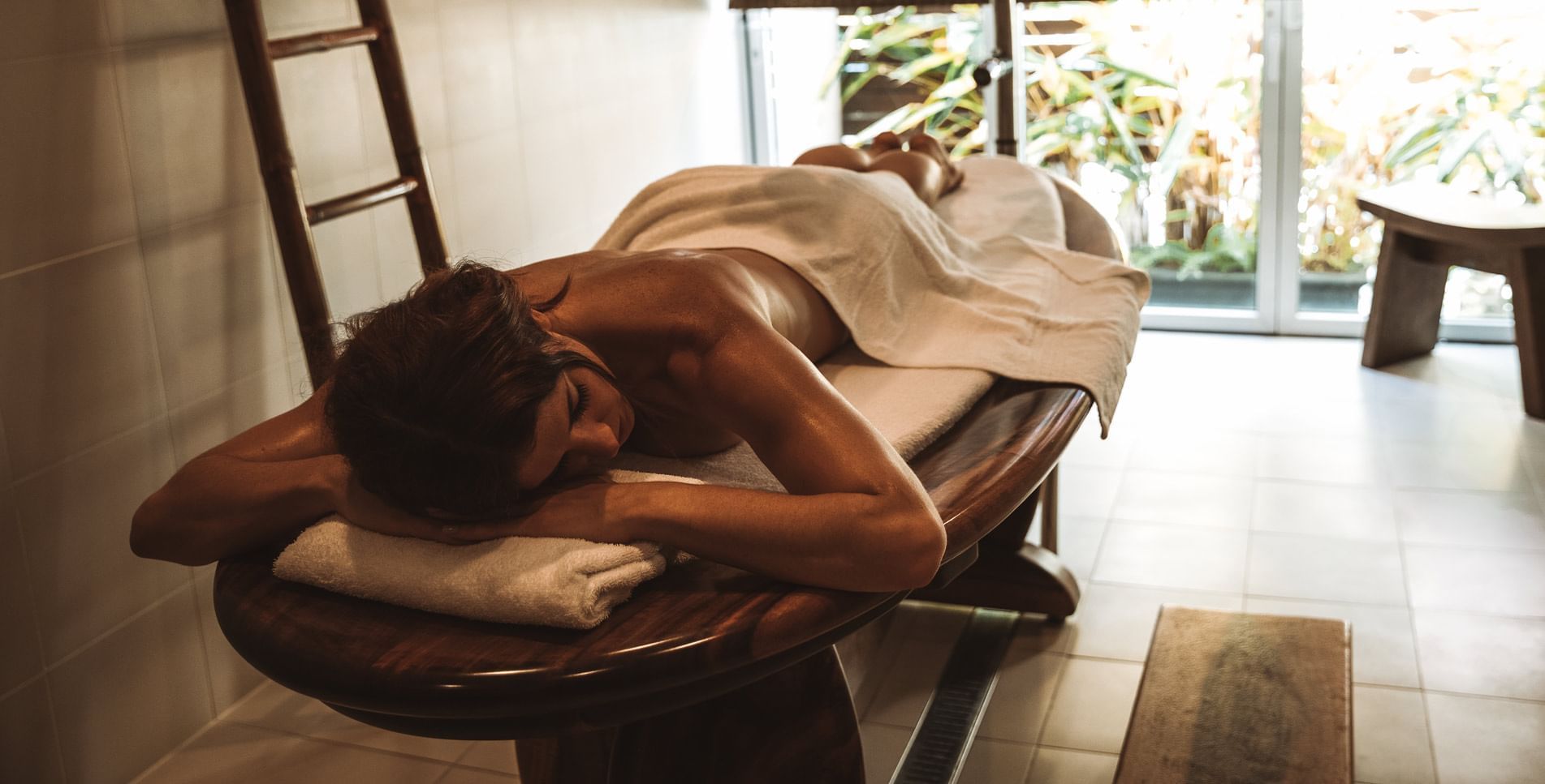 A woman relaxing on a massage bed in a spa at Pullman Cairns