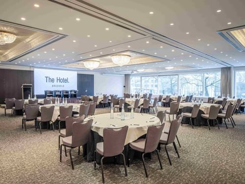 Banquets set up facing a large screen by the window in Grand Ballroom at The Hotels Brussels