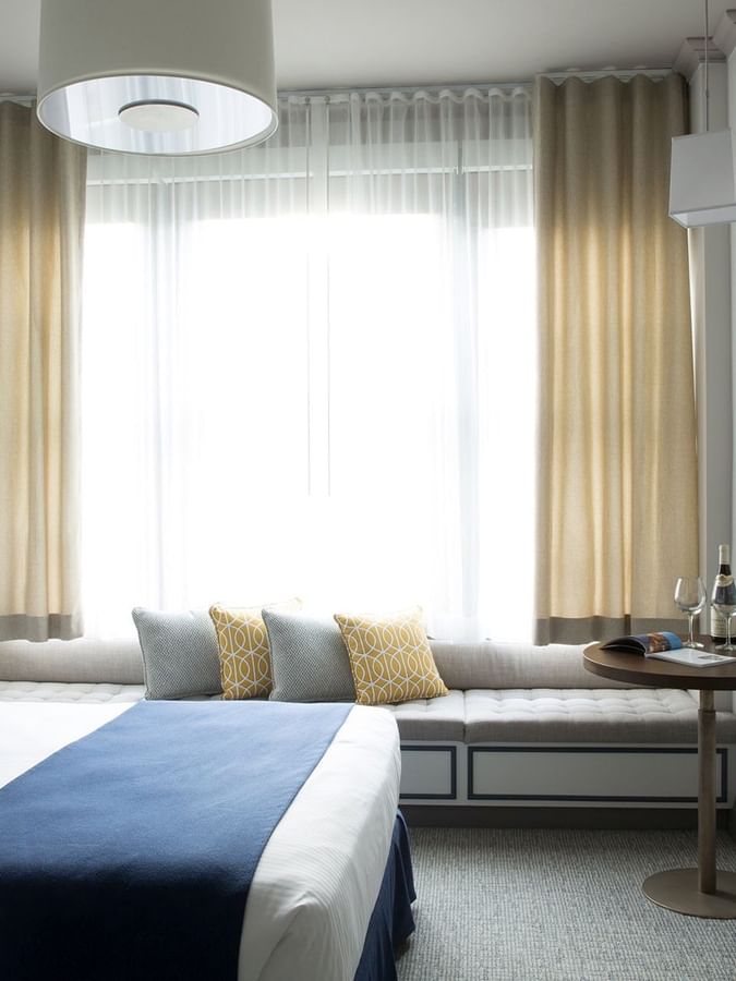 Small round table by a cushioned window seat under a pendant lamp in Deluxe Queen Room at Warwick San Francisco