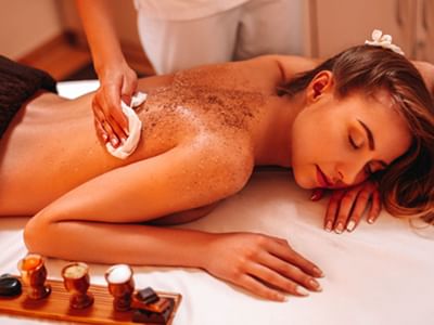 Woman receiving a relaxing body scrub treatment on her back by a spa professional at Sugar Cane Club Hotel & Spa