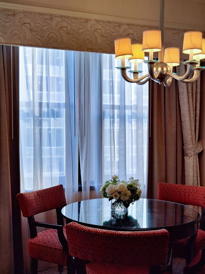 Elegant dining area with a round table and red chairs in On the Avenue One Bedroom Suite at Warwick New York