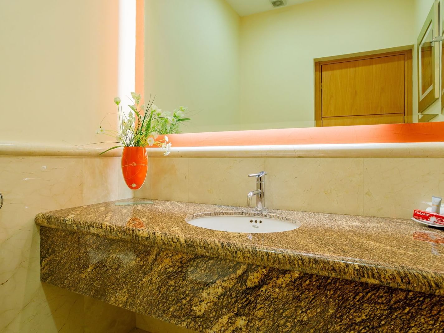 King Presidential Suite bathroom vanity featuring a granite countertop, orange vase, and bright lighting at Real Inn Torreon