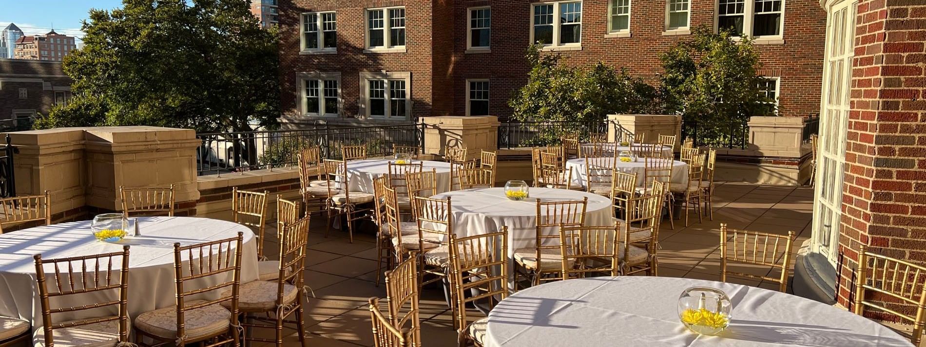 Round event tables by gold chairs under a clear sky in The Bridewell Suite at Warwick Melrose Dallas