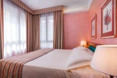 Cozy bed with nightstand & a view in Executive Suite at Hotel Crivi's in Milan