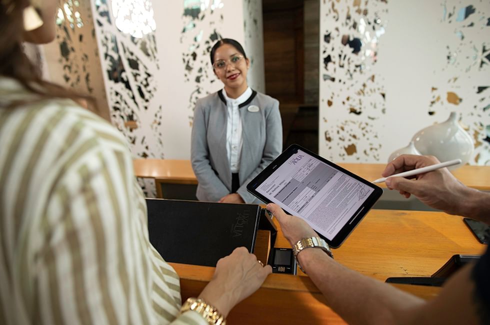 Two individuals reviewing a document on a tablet at Live Aqua Resorts and Residence Club