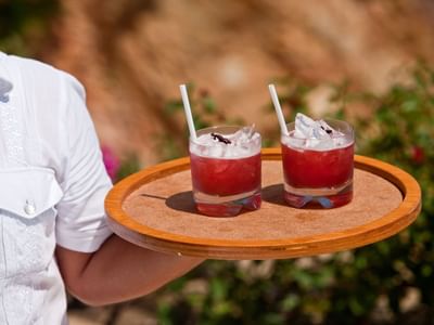 A chef holding 2 juice glasses on a tray at Cala de Mar