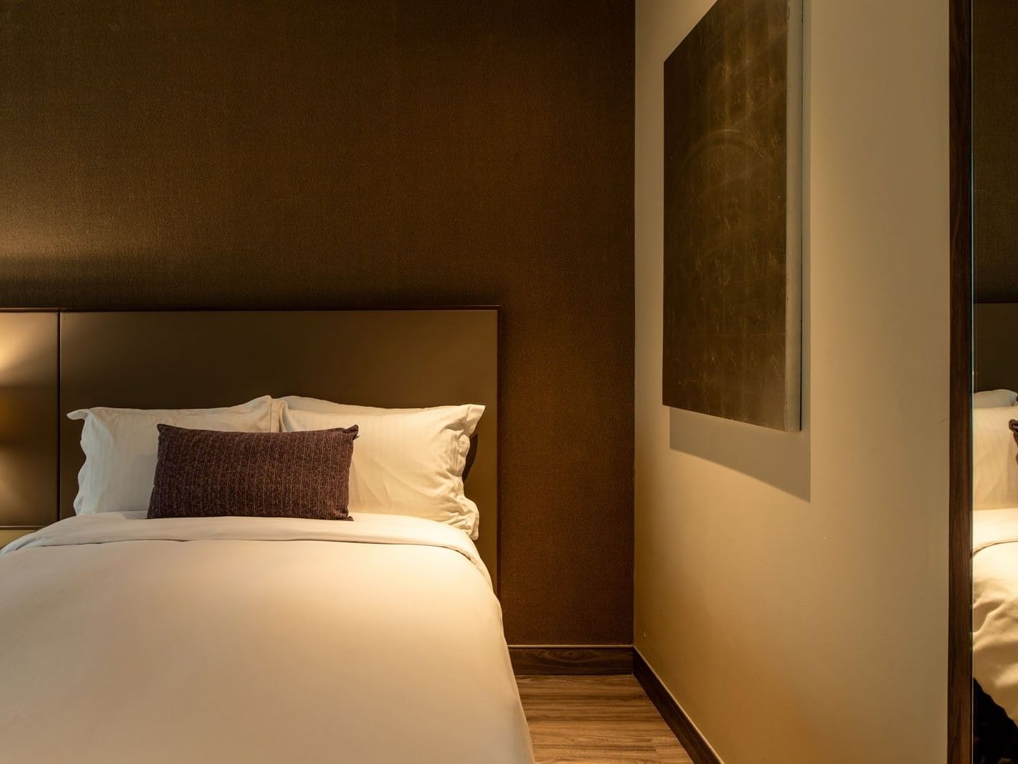 Close-up of a 2 Double Deluxe bed with white linens and a brown textured wall at Camino Real Fashion Drive, Monterrey