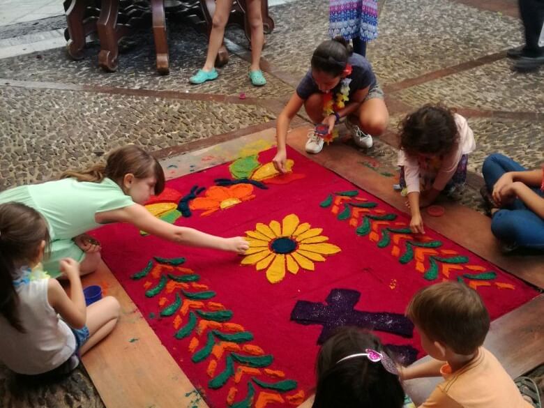 Kids creating a flower design on a red mat at Porta Hotel Antigua