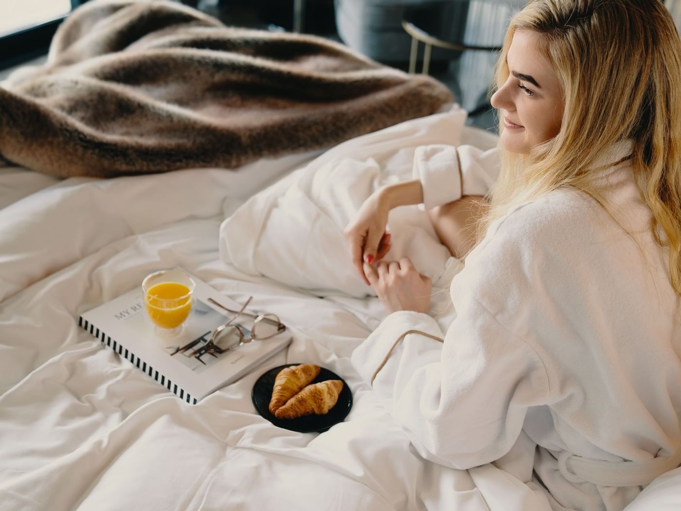 En kvinna som äter frukost i en säng på Hotel Riverton.