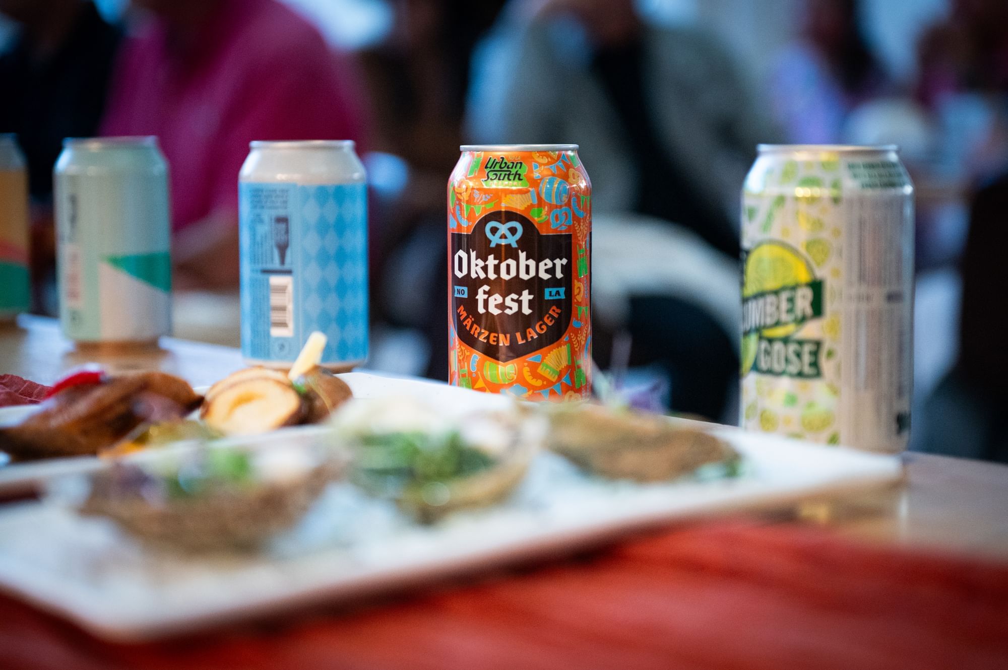 Four cans of beer on a table with food, including one labeled