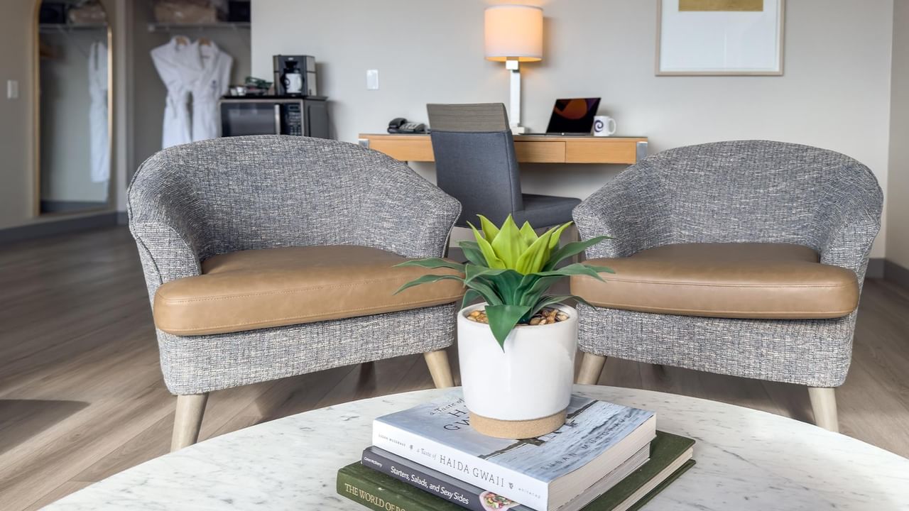 Two armchairs with a potted plant on a table at Coast Chilliwack Hotel by APA.