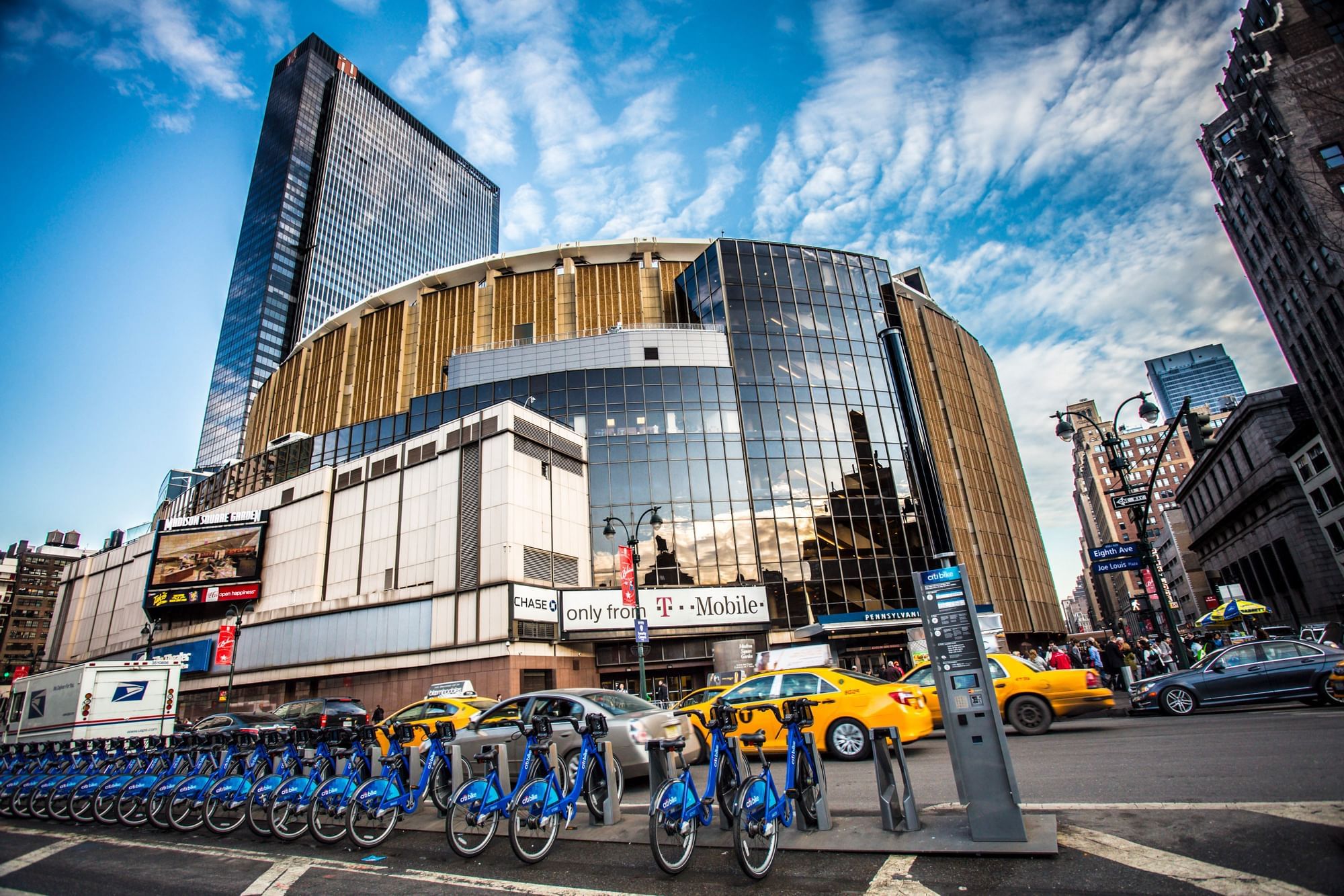 A curved glass and gold exterior of a building on a city street with cars and bicycles.