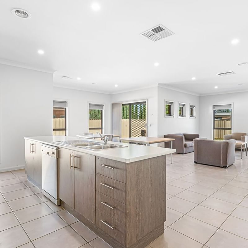 Brightly lit kitchen and living room area with modern furniture and appliances at La Trobe University Regional Housing – Mildura.
