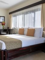 Comfortable bed and separate single bed beside small working area in Lagoon View Room at warwick le lagon-vanuatu