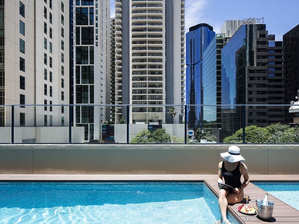 Lady sitting near the pool at Sebel Suites Brisbane