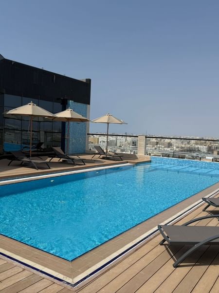 Outdoor pool with lounge chairs and umbrellas at Skyfall Lounge, Warwick Hotel & Spa - Jeddah.