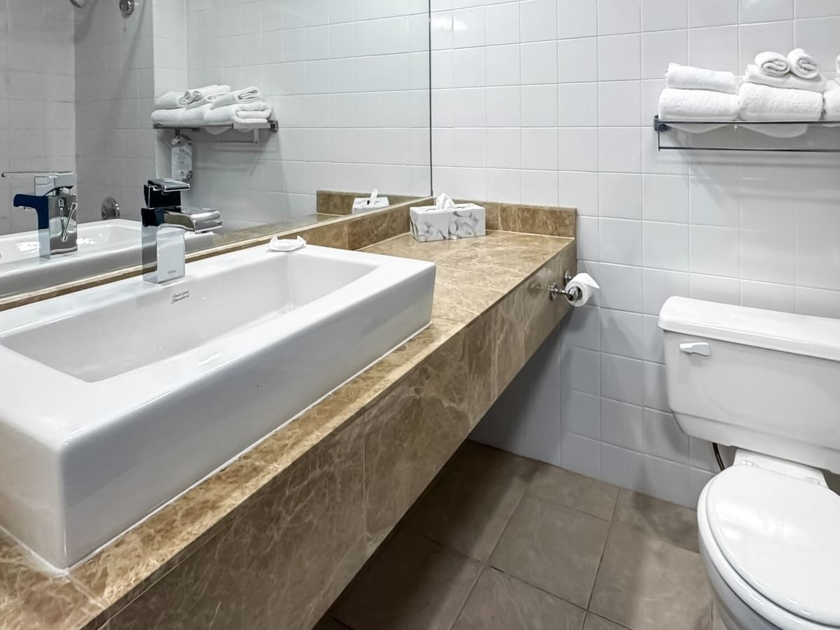 Coast Premium King with Patio bathroom with sink, toilet, and towel rack with folded towels at Coast Lonsdale Quay Hotel