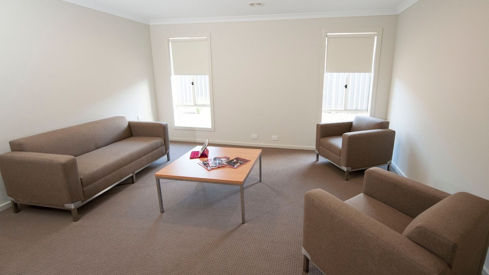 Living room with couch, coffee table, and chairs at La Trobe University Regional Housing – Shepparton.