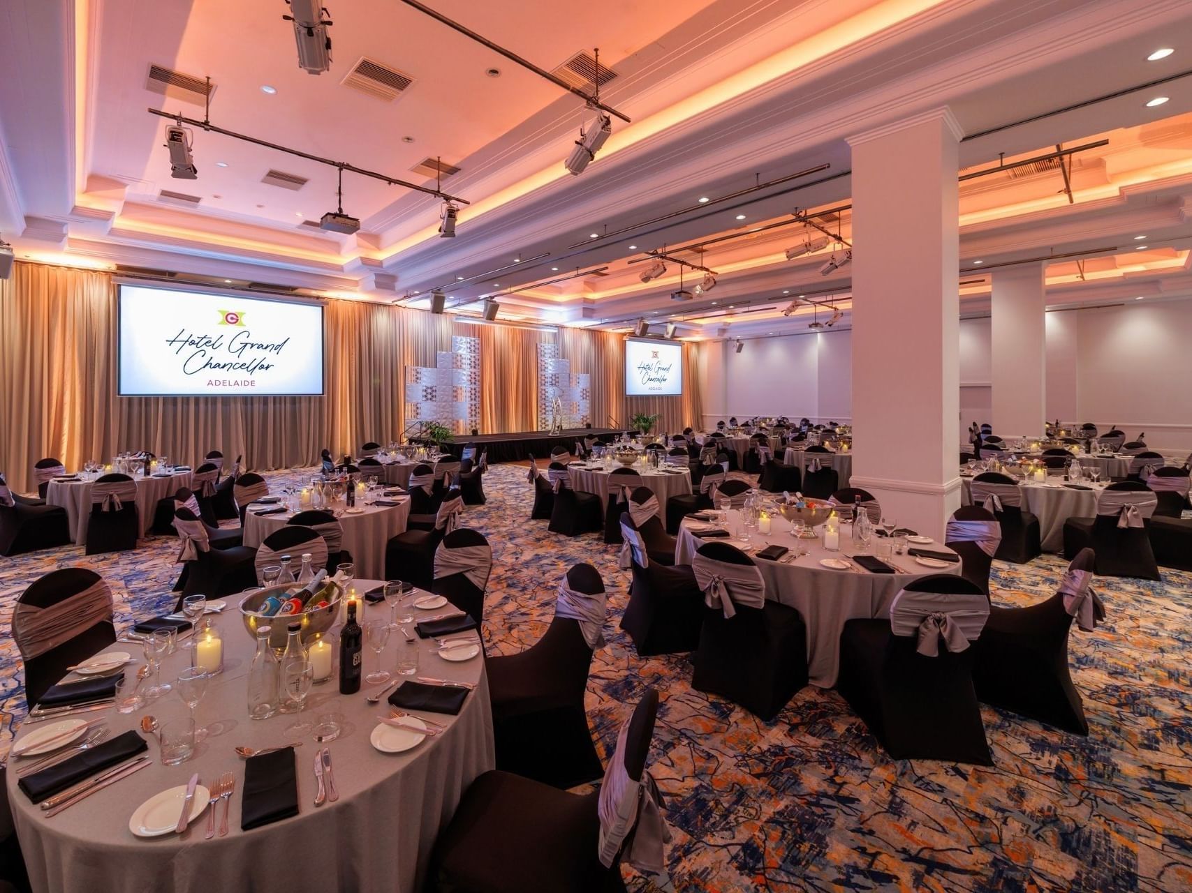 Decorated ballroom with round tables and black chairs at Hotel Grand Chancellor Adelaide.