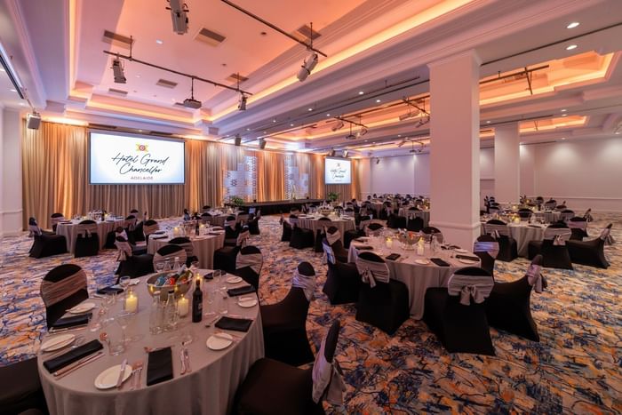 Elegantly set banquet hall with round tables and large screens at Hotel Grand Chancellor Adelaide