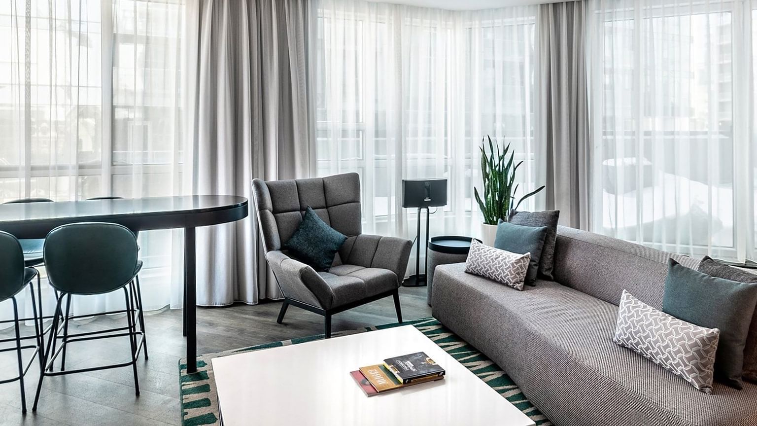 Living room with couch, table, and chairs in a hotel suite promoting Long Stay Privileges.