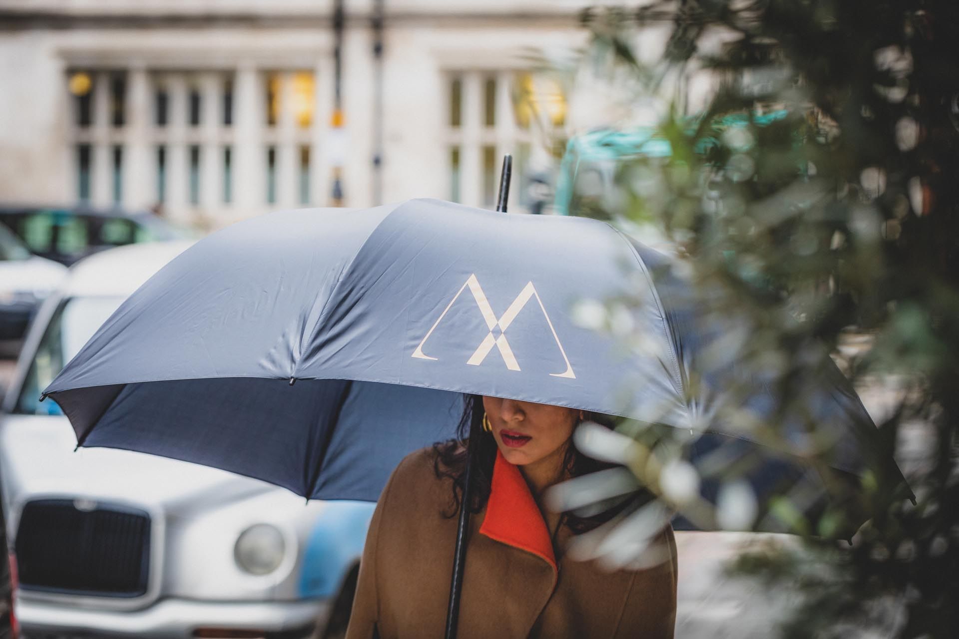 A girl holding an umbrella near The May Fair Hotel London