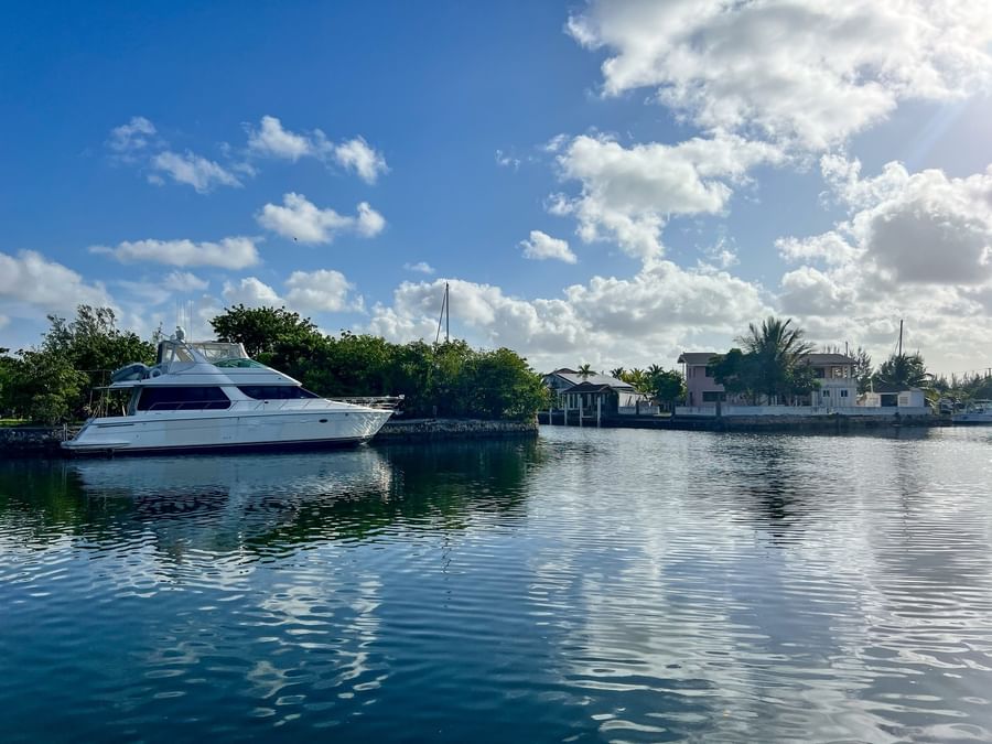 White yacht by a green shoreline under a cloudy sky surrounding calm canal water near Warwick Paradise Island Bahamas