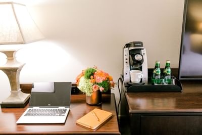 table with coffee maker, flowers and laptop