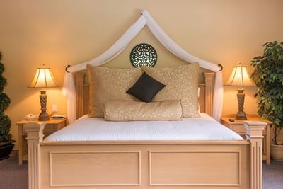 Canopy bed positioned between two nightstands with lamps in Tuscany Themed Suite at Hilltop Inn, Salmon Arm