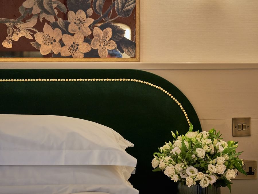 White bouquet beside green velvet studded headboard under floral art at The Capital Hotel, Apartments & Townhouse