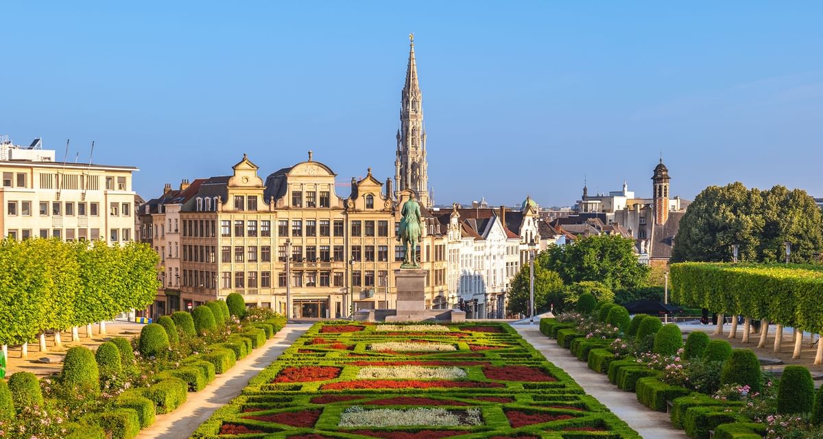 Historic square statue placed by a colorful garden path near Warwick Grand Place Brussels