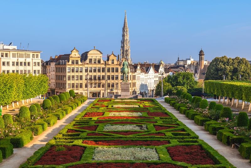 Historic square statue placed by a colorful garden path near Warwick Grand Place Brussels