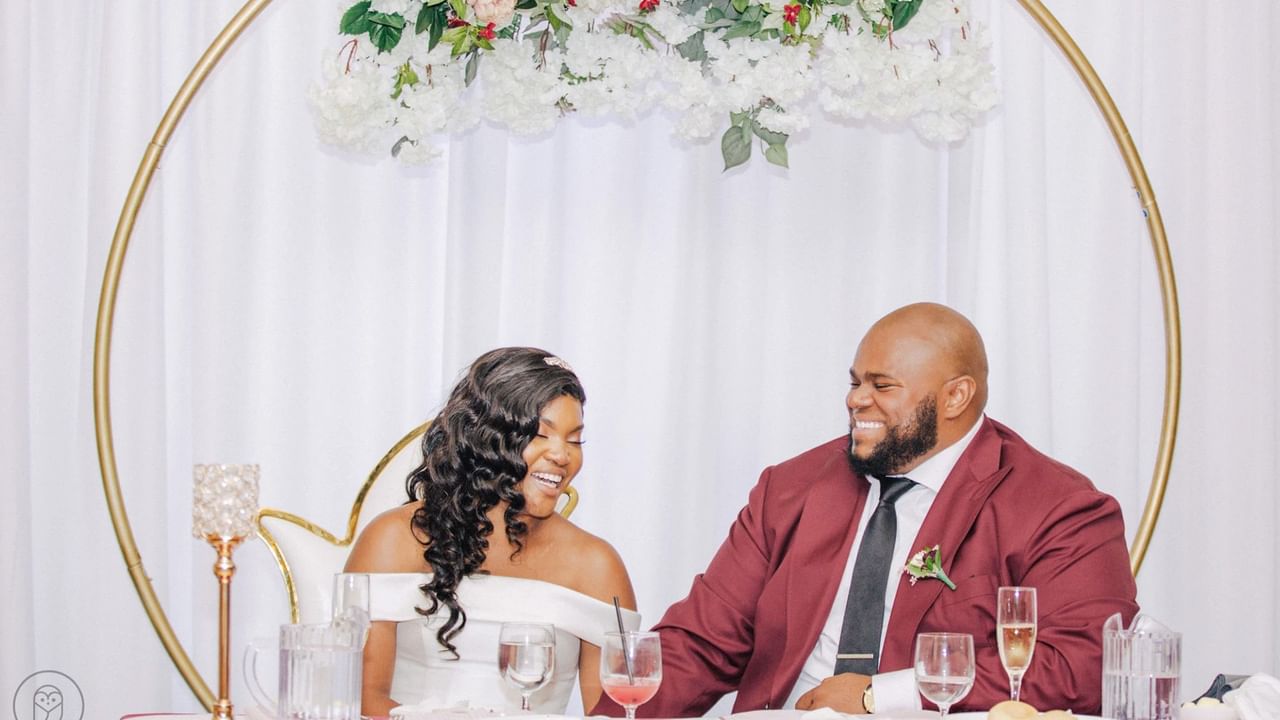 A newlywed couple sits and laughs together at the head table of their Canmore wedding venue.