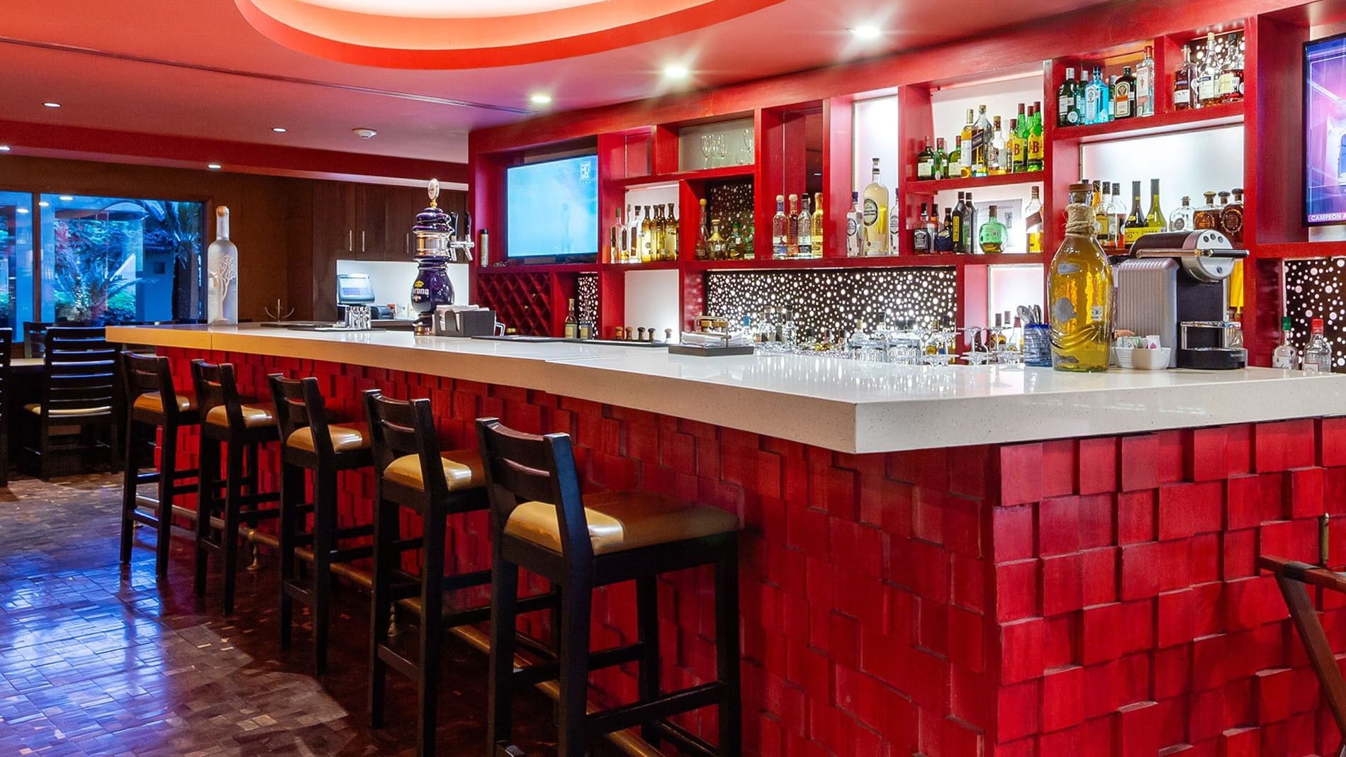 Stylish Maria Bonita bar at Camino Real Guadalajara, with a textured red base, white counter, and premium spirits