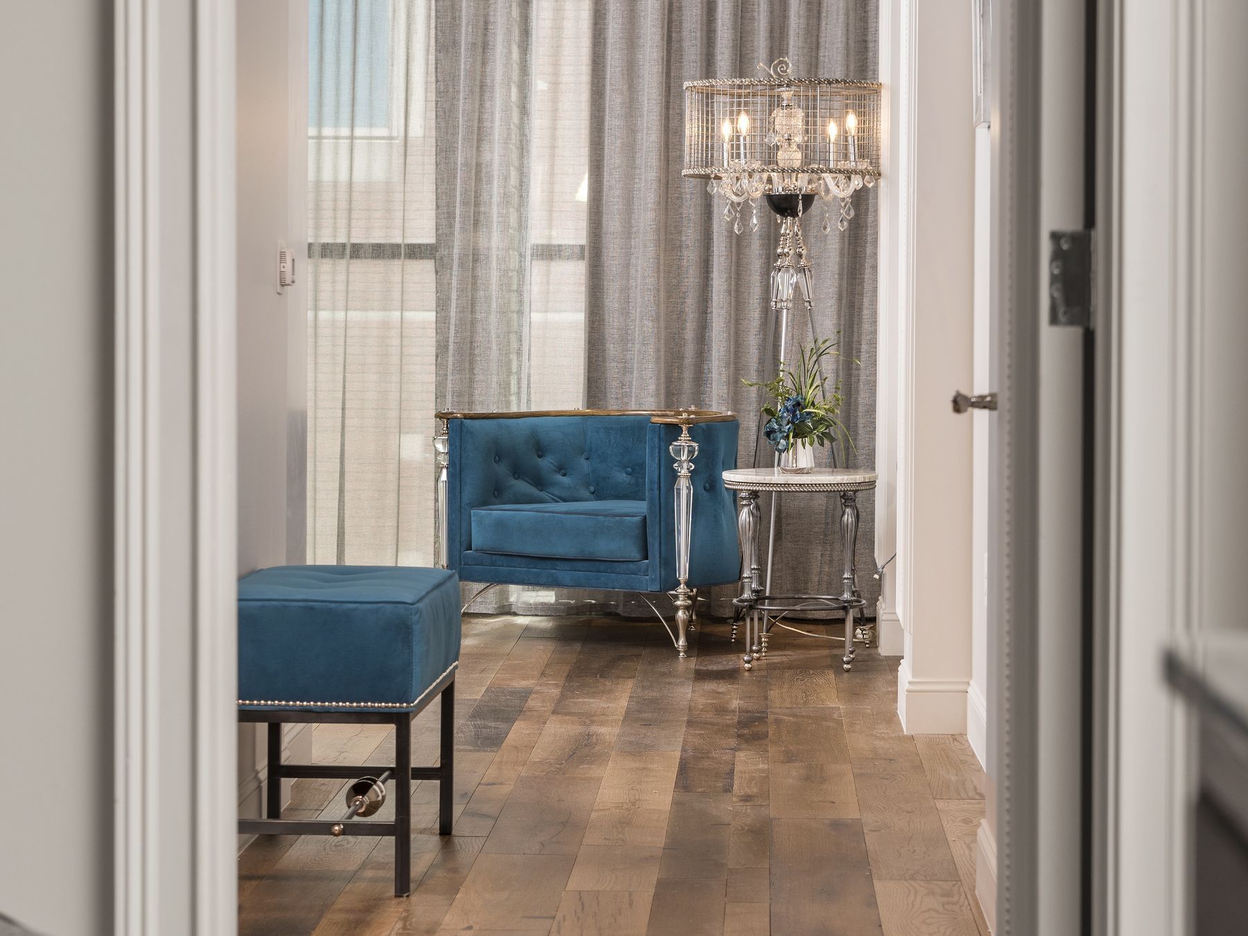 A luxurious room with a blue armchair, ottoman, and chandelier.